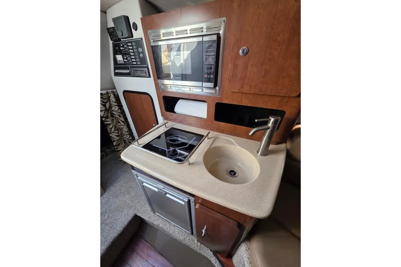Slide: The Image of 2022 Crownline 264 CR boat interior with kitchenette, sink, and modern appliances. - 10