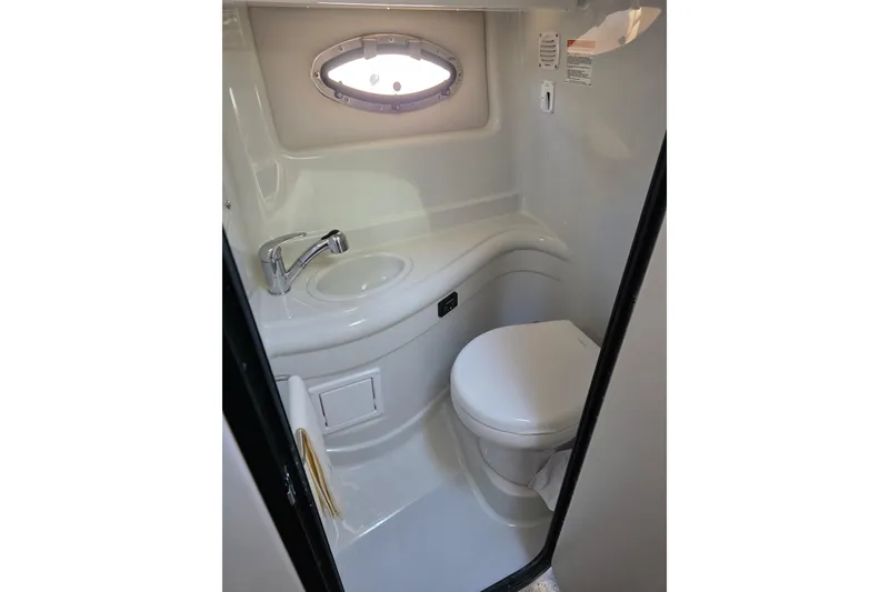 Slide: The Image of 2022 Crownline 264 CR boat bathroom with sink, toilet, and porthole window. - 11