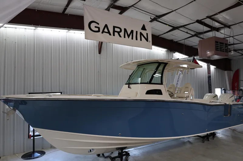 The Image of 2026 Grady-White Canyon 306 boat displayed indoors under Garmin banner. - 0