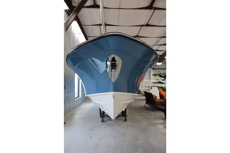 Slide: The Image of 2026 Grady-White Canyon 306 boat in indoor showroom, blue and white hull. - 1