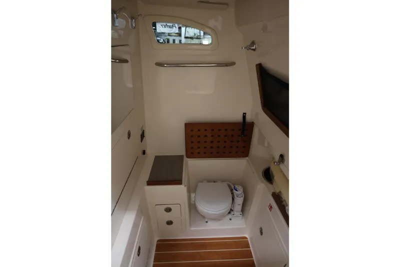 Slide: The Image of 2026 Grady-White Canyon 306 boat interior with compact bathroom and wooden accents. - 12