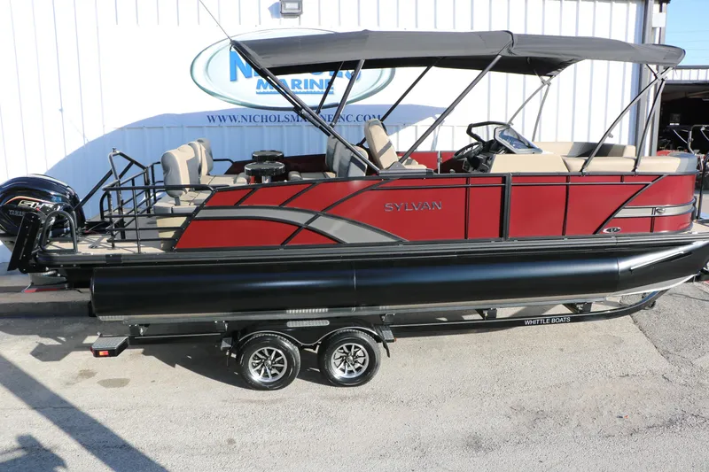 Slide: The Image of 2026 Sylvan L3 RLZ pontoon boat with red and black design, parked on a trailer. - 11