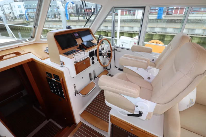 Slide: The Image of 2019 Back Cove 41 yacht helm with dual beige captain chairs and modern navigation equipment. - 19