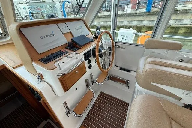Slide: The Image of 2019 Back Cove 41 boat cockpit with Garmin navigation, wooden accents, and beige seating. - 20