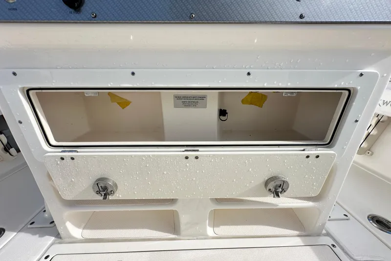 Slide: The Image of 2018 Blackwood 27 Bayboat storage compartment with dual latches, showcasing interior space. - 18