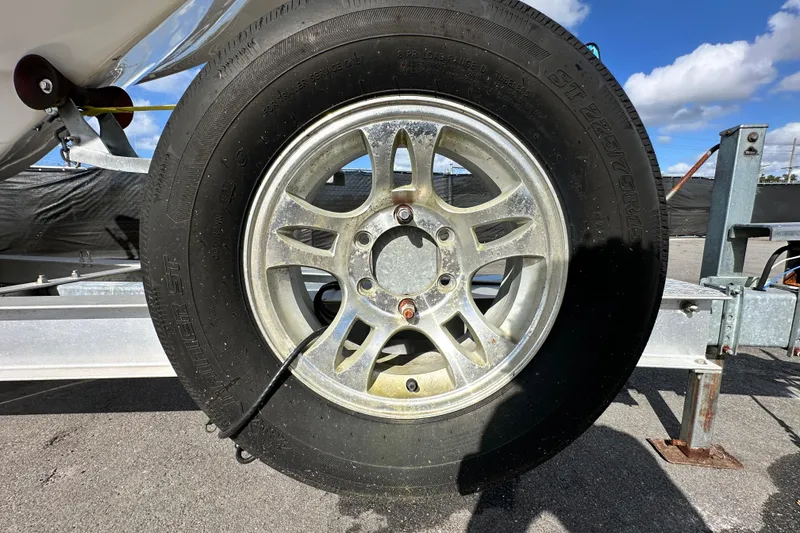 Slide: The Image of Trailer wheel of a 2018 Blackwood 27 Bayboat under clear blue sky. - 94
