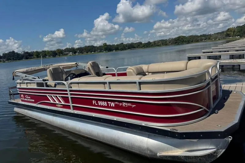 The Image of 2023 Sun Tracker Party Barge 24 DLX pontoon boat docked on a sunny lake. - 1