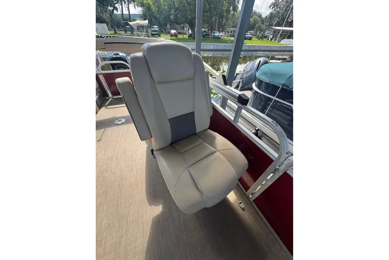 Slide: The Image of 2023 Sun Tracker Party Barge 24 DLX boat seat, beige upholstery, docked by water. - 5
