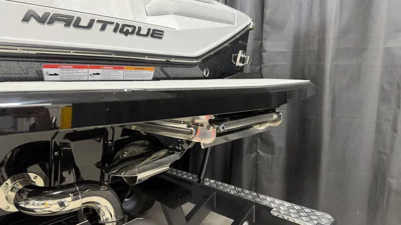 Slide: The Image of The rear of a Nautique boat with shiny exhaust pipes and warning labels. - 10