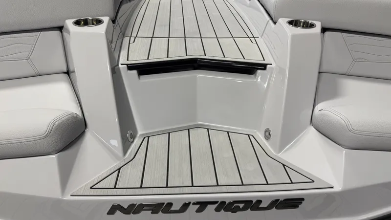 Slide: The Image of The image shows the stern of a Nautique boat with gray decking and seating areas. - 13
