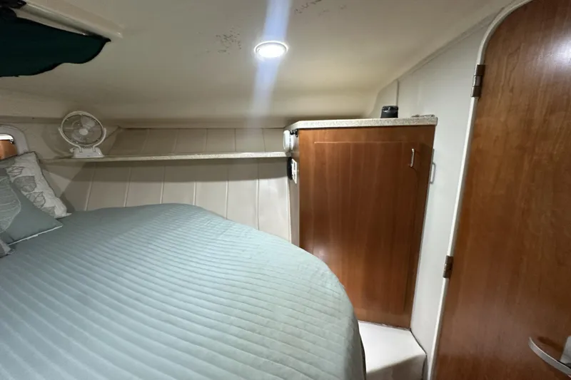 Slide: The Image of 1998 Mainship 40 Sedan Bridge cabin interior with bed, fan, and wooden cabinet. - 9