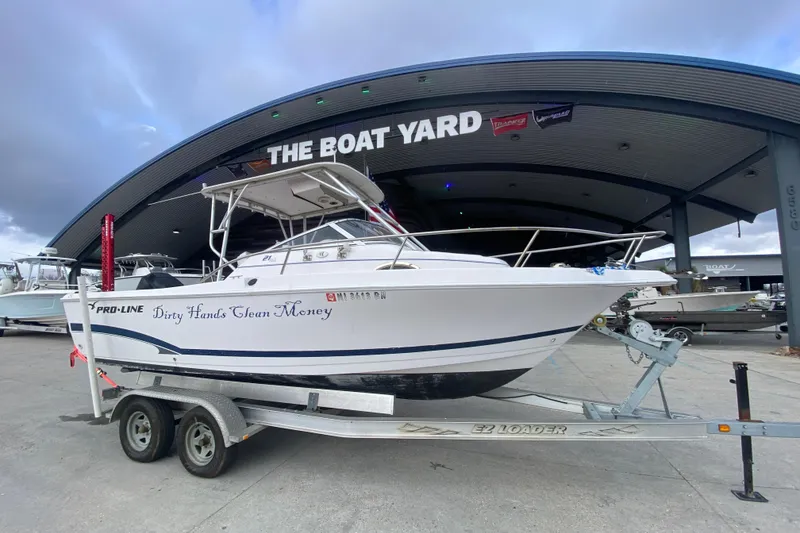 Slide: The Image of 2005 PROLINE 21 boat on trailer at The Boat Yard, featuring "Dirty Hands Clean Money" text. - 2