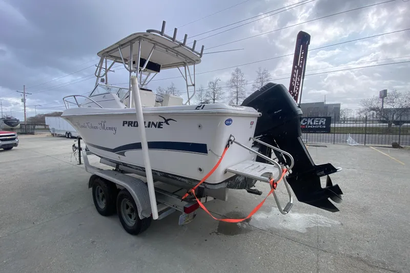 Slide: The Image of 2005 PROLINE 21 boat on trailer with outboard motor, parked outdoors under cloudy sky. - 6