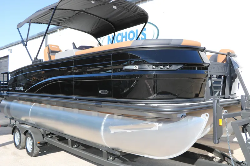 Slide: The Image of 2026 Sylvan L3 DLZ Bar Tri-Toon pontoon boat with sleek black design on trailer. - 4