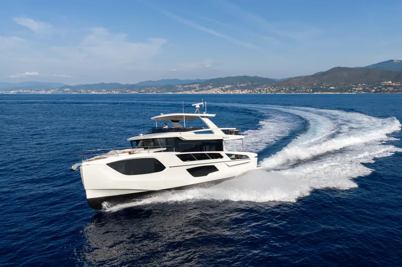 Slide: The Image of Luxurious 2027 Absolute Navetta 66 yacht cruising on open sea with scenic coastline backdrop. - 2