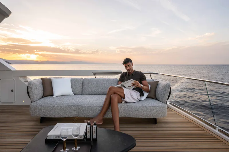 Slide: The Image of Man relaxing on Absolute Navetta 66 yacht deck at sunset, reading a magazine. - 32
