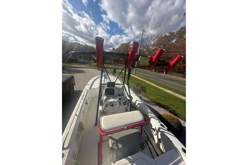Slide: The Image of 2006 Mako 224 Center Console boat with red rod holders, parked on a driveway. - 2