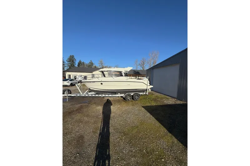 Slide: The Image of 2023 Parker Poland 660 Weekend boat on trailer, parked outdoors under clear blue sky. - 14