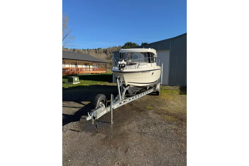 Slide: The Image of 2023 Parker Poland 660 Weekend boat on trailer, parked outdoors under clear blue sky. - 16