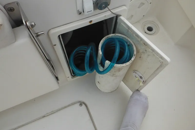Slide: The Image of Open storage compartment with blue hose on 2006 Seaswirl Striper 2301 Dual Console O/B boat. - 20