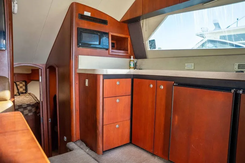 Slide: The Image of 2004 Luhrs 36 Convertible yacht interior with wooden cabinetry and compact kitchen area. - 29