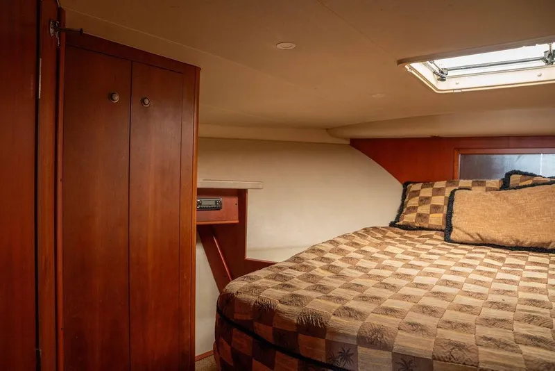 Slide: The Image of 2004 Luhrs 36 Convertible cabin interior with bed, wooden cabinets, and overhead hatch. - 44