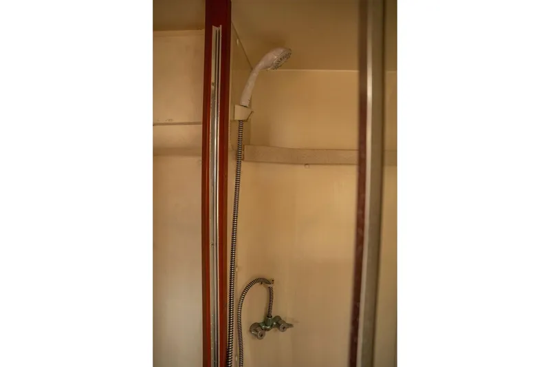 Slide: The Image of Shower area in 2004 Luhrs 36 Convertible boat, featuring handheld showerhead and beige interior. - 47