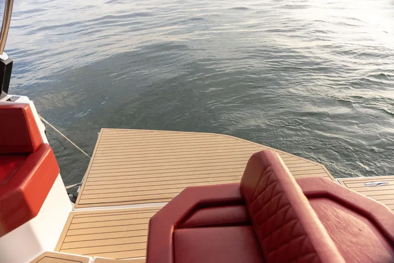 Slide: The Image of 2026 Hanover 387 boat with red seating and wooden deck on calm water. - 12