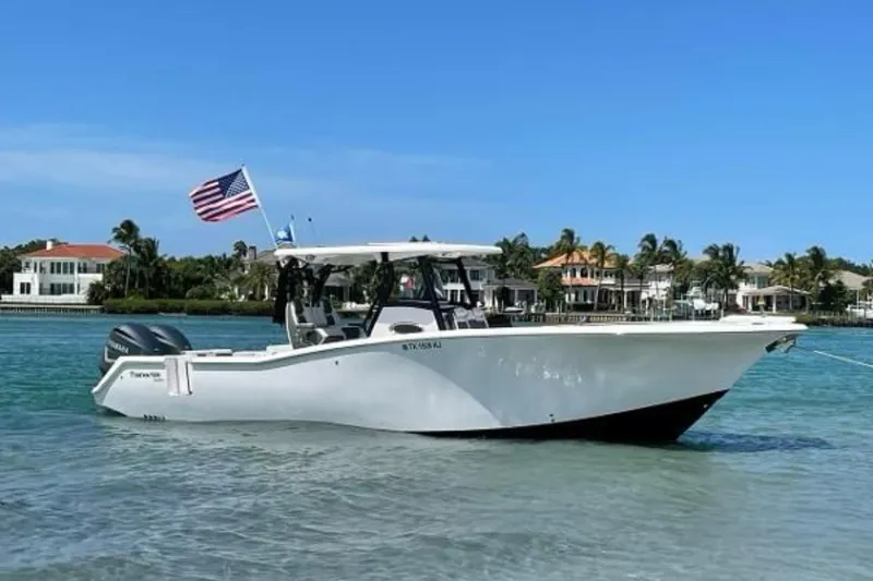 The Image of 2020 Tidewater 320 CC Adventure boat anchored in clear water, American flag waving. - 0