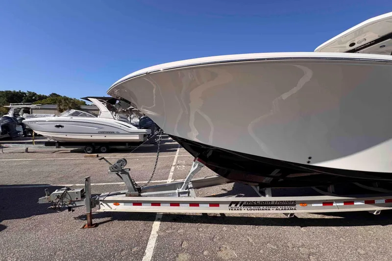 Slide: The Image of 2020 Tidewater 320 CC Adventure boat on trailer under clear blue sky. - 8