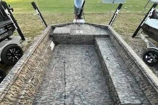 Slide: The Image of 2024 Xpress H18DB boat with camouflage interior, parked on grass. - 6