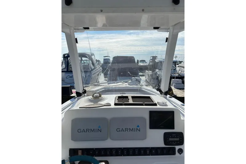 Slide: The Image of 2013 Sea Hunt Gamefish 25 dashboard with Garmin navigation, docked among other boats. - 4