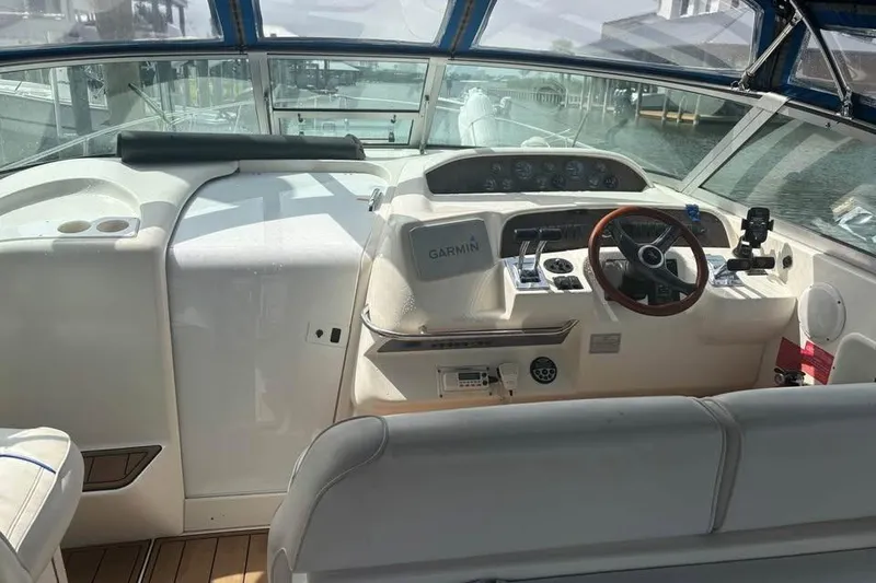 Slide: The Image of 1996 Sea Ray 330 Sundancer cockpit with Garmin navigation, wooden steering wheel, and marina view. - 5