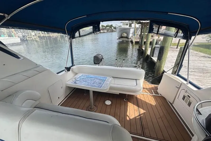Slide: The Image of 1996 Sea Ray 330 Sundancer interior with seating and table, overlooking marina. - 6