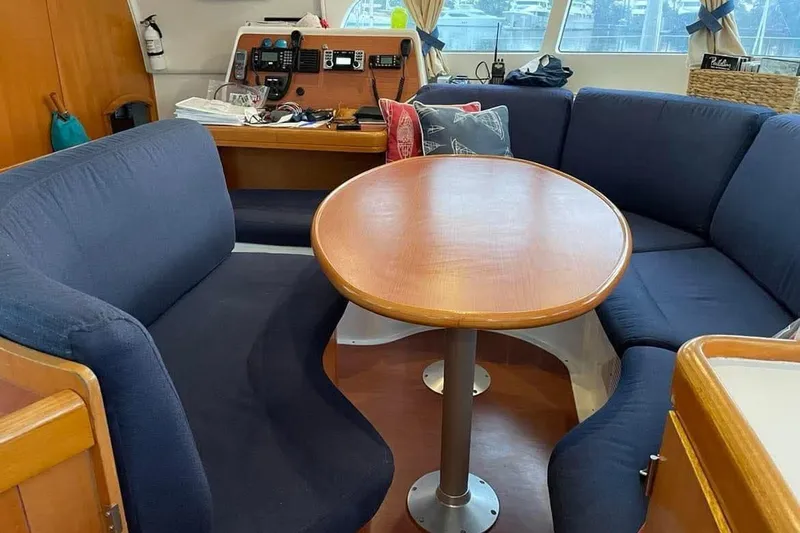 Slide: The Image of Interior of 2006 Lagoon 410-S2 catamaran with blue seating and wooden table. - 11