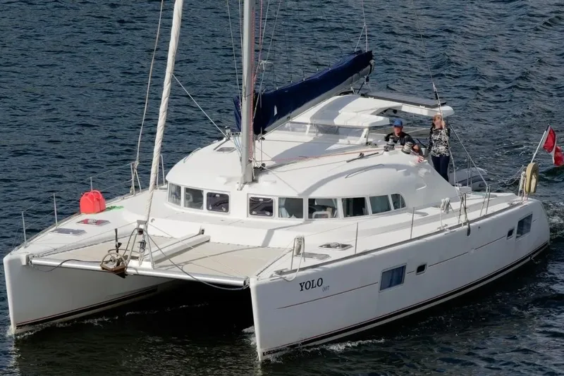 The Image of 2006 Lagoon 410-S2 catamaran sailing on open water with two people on deck. - 0