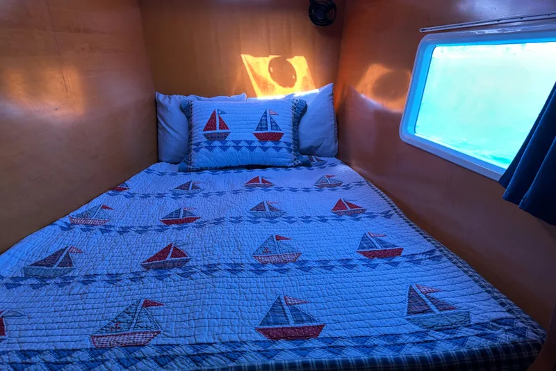 Slide: The Image of Cozy cabin bed in 2006 Lagoon 410-S2 with nautical-themed quilt and window view. - 16