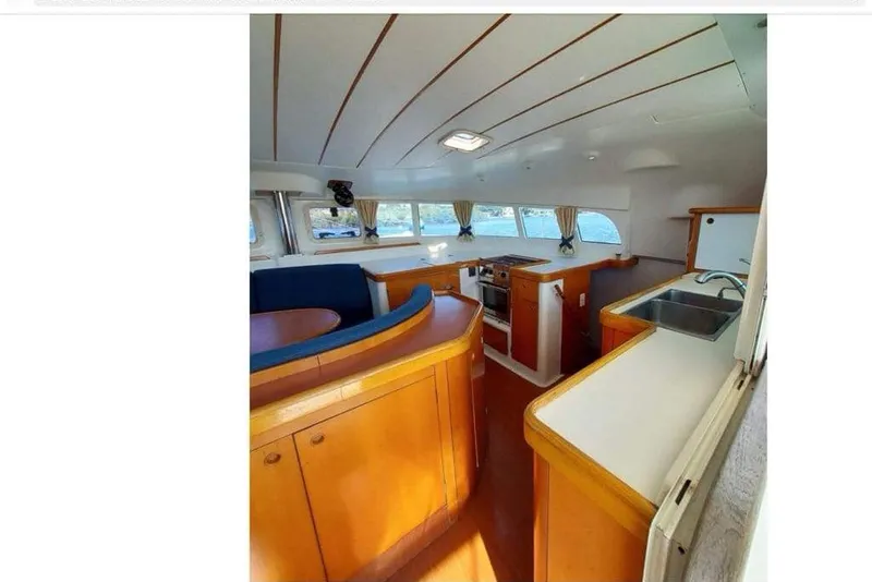 Slide: The Image of Interior of 2006 Lagoon 410-S2 catamaran with kitchen and seating area. - 7