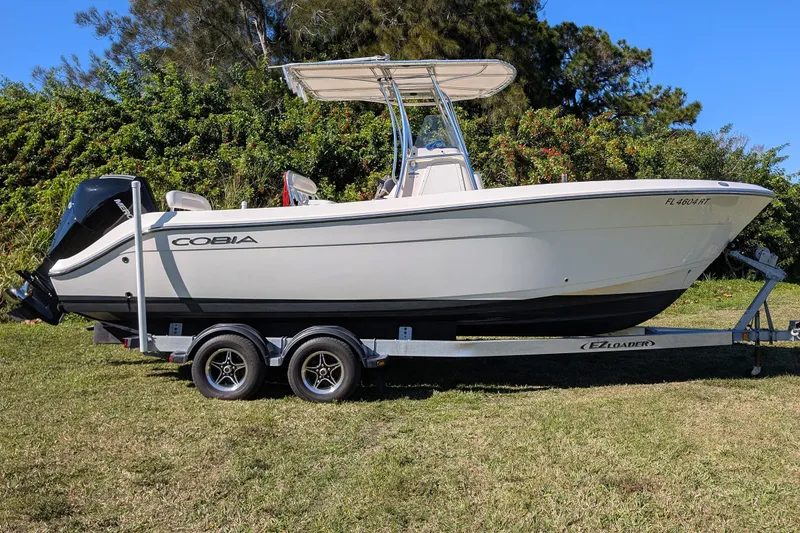 Slide: The Image of 2019 Cobia 237 Center Console boat on trailer, parked on grass. - 3