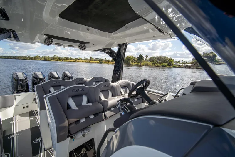 Slide: The Image of Interior view of 2020 MTI V42 boat with luxurious seating and multiple engines on a scenic lake. - 32