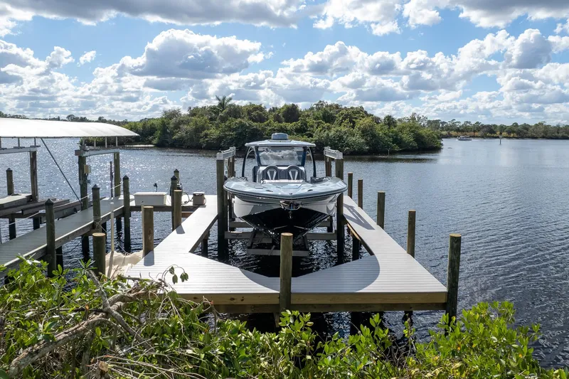 Slide: The Image of 2020 MTI V42 boat docked on a serene lake under a partly cloudy sky. - 47