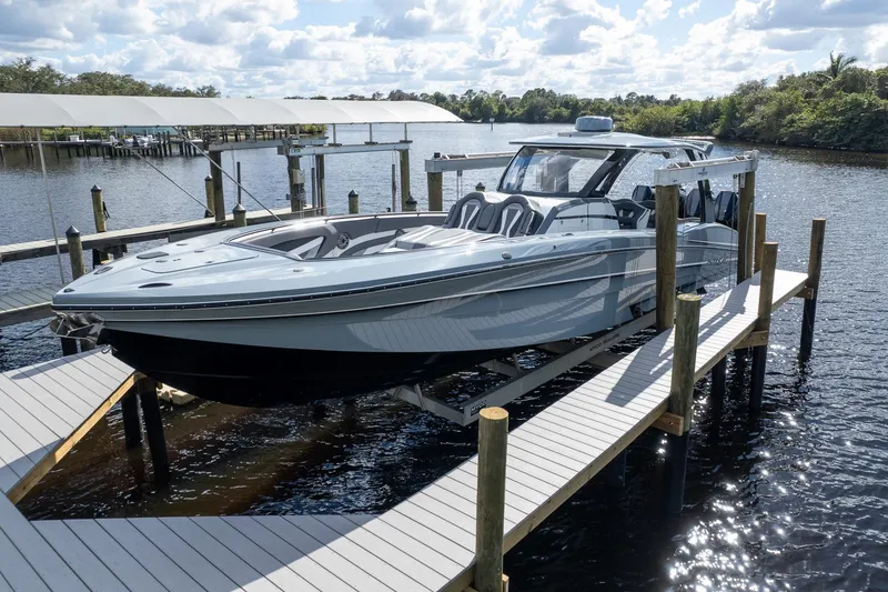 Slide: The Image of 2020 MTI V42 boat docked on a lift, surrounded by calm water and a scenic backdrop. - 49