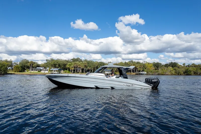 Slide: The Image of 2020 MTI V42 boat cruising on a sunny day with scenic shoreline background. - 72