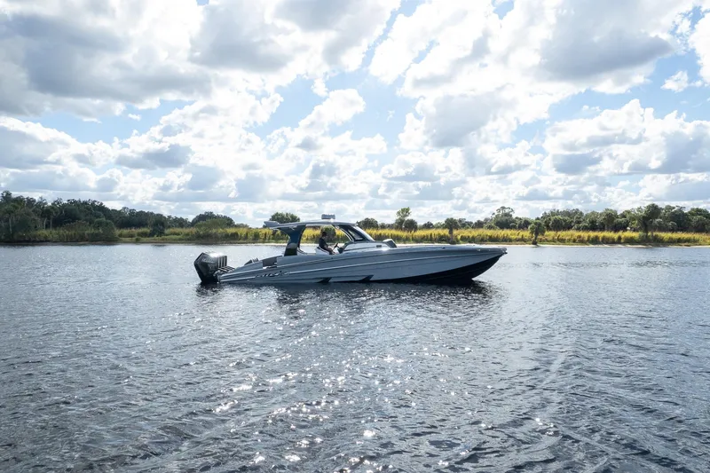 Slide: The Image of 2020 MTI V42 boat cruising on a serene lake under a partly cloudy sky. - 86