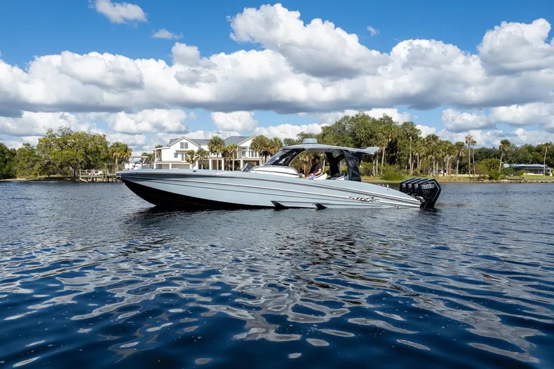 Slide: The Image of 2020 MTI V42 boat cruising on a scenic lake under a blue sky with clouds. - 92