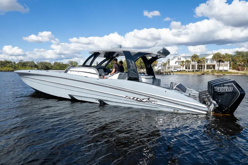 Slide: The Image of A sleek 2020 MTI V42 boat on a sunny day, cruising near waterfront homes. - 94