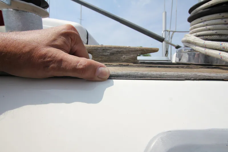 Slide: The Image of Hand inspecting deck of 1990 Nautor Swan 61 yacht, showing wood and rope details. - 19