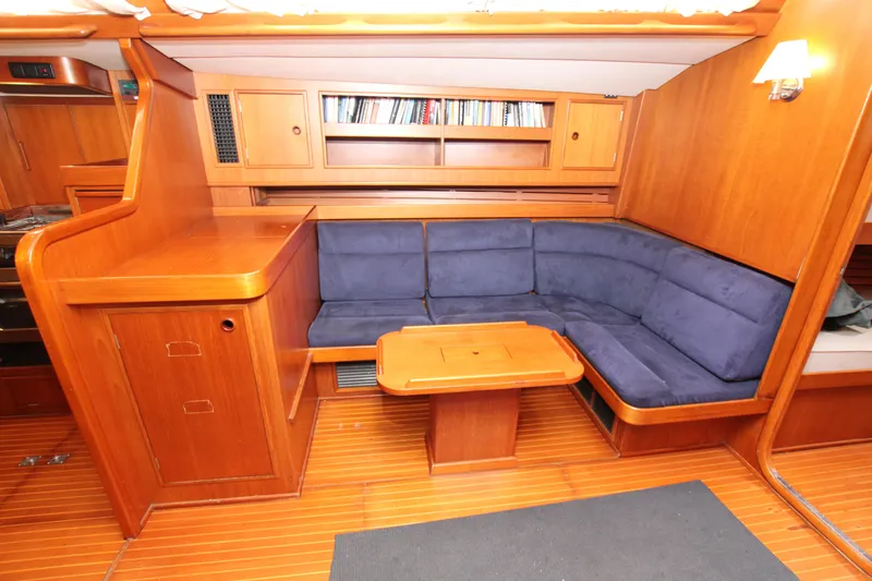 Slide: The Image of Luxurious 1990 Nautor Swan 61 yacht interior with wooden cabinetry and blue cushioned seating. - 31