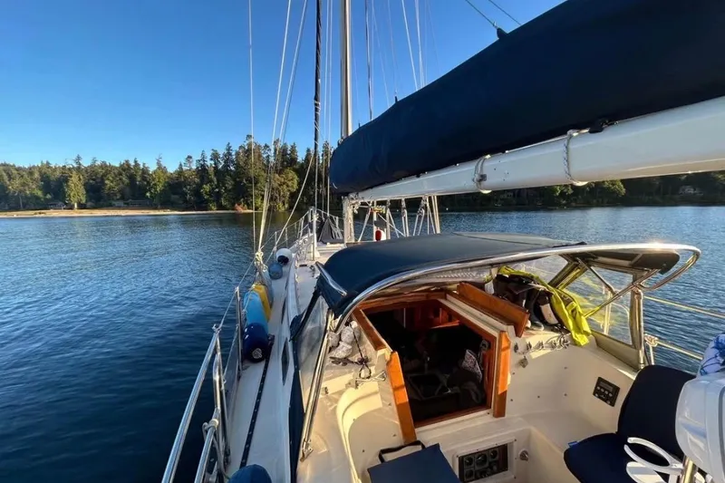 Slide: The Image of 1990 Pacific Seacraft PSC 37 sailboat on calm water, surrounded by lush trees. - 4