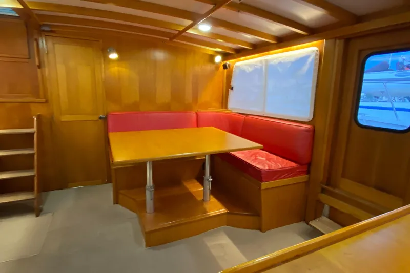 Slide: The Image of Interior of 1987 Jarvis Newman 46' Flybridge Cruiser with wooden dining area and red seating. - 17